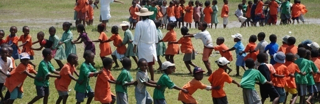 Large group of children playing a game in a field.