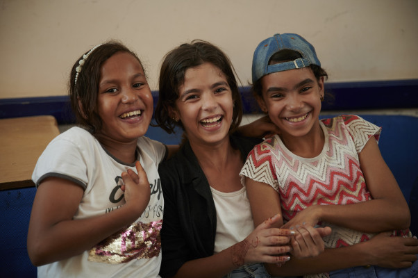 Three girls with their arms around each other smiling at the camera