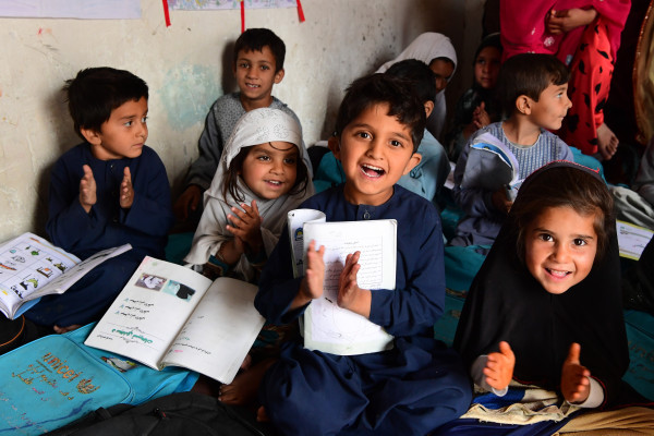Children in classroom smiling at desks.